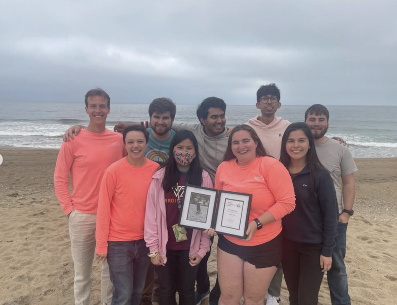 Nine members of the SailBot team with their 2nd place plaque on the beach.
