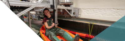 student in a kayak inspecting the tow tank carriage