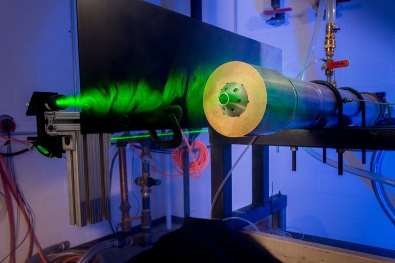 A laser illuminates the flowfield of a free jet for Doppler-based speed measurements.