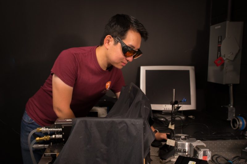 Chi-Young Moon, a Ph.D. student in AOE, fine tunes hardware for an advanced laser-based instrument.