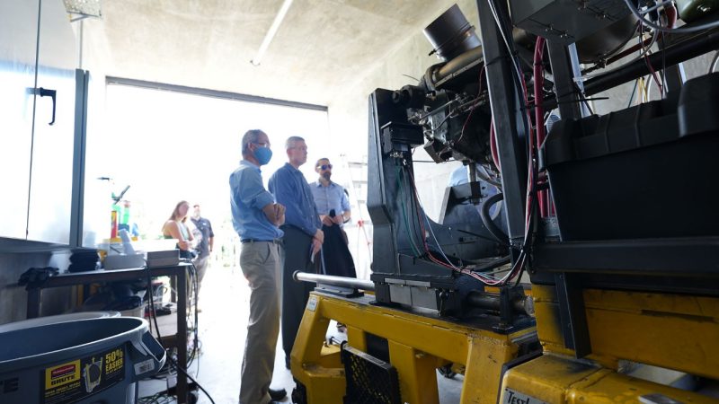 Wing Ng, Brian Warner, and Todd Lowe stand at the Rolls-Royce engine used for research in the Virginia Tech Advanced Power and Propulsion Laboratory.