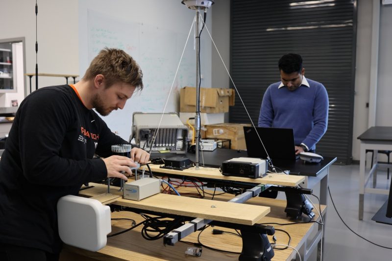 Casey Smith and Sandeep Jada work on a multi-sensor system, to be affixed on a roof rack of a vehicle for field testing. 